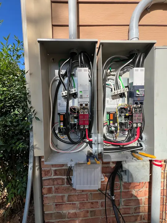 Two 200 amp automatic transfer switches wired on the side of a house