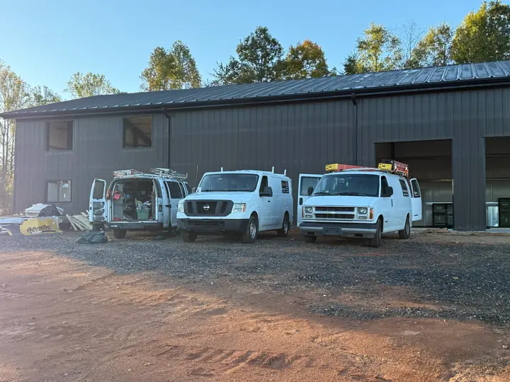 Three AP Electric work vans parked in front of a new metal building